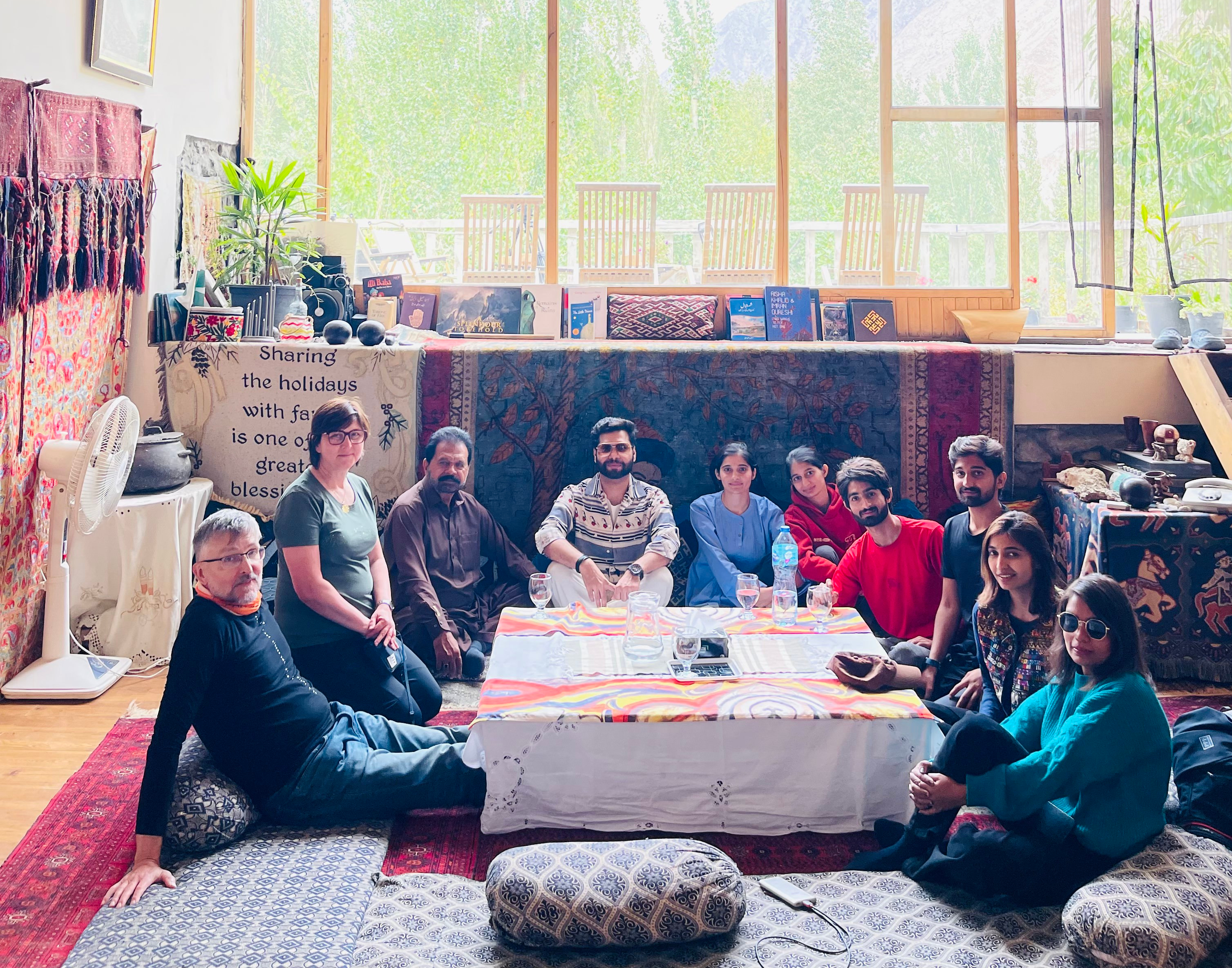 Travelers sharing tea with Kalash elders on a wooden veranda